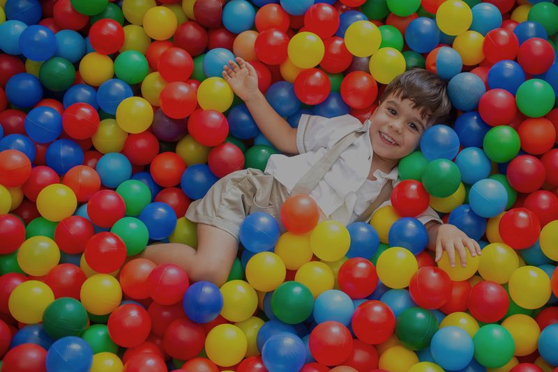 Menino deitado numa piscina de bolinhas coloridas